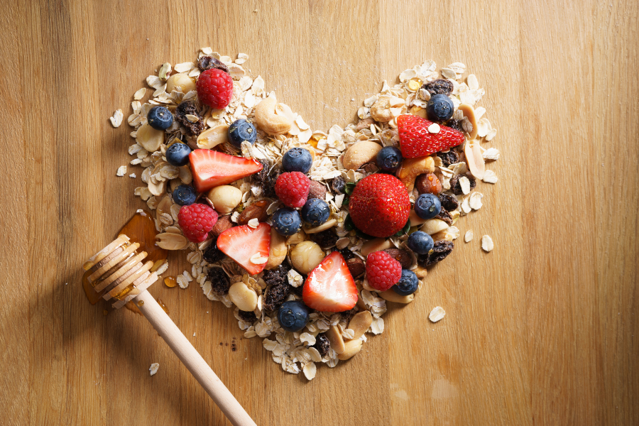 Goûter sain et fait maison en forme de cœur, composé de flocons d’avoine, fruits rouges et miel : une collation équilibrée idéale pour une pause gourmande en accord avec de bonnes habitudes alimentaires, loin du grignotage émotionnel.