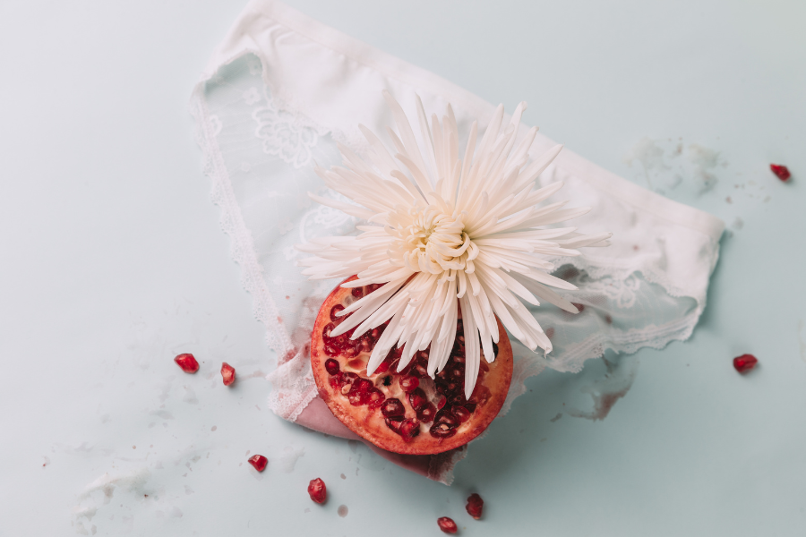 Image artistique représentant la féminité et la fin des cycles menstruels, avec une fleur et une grenade sur une culotte blanche. La ménopause est une étape pas une fatalité!