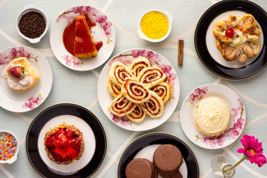 Assortiment de pâtisseries et desserts riches en sucre, comme des gâteaux, roulés à la confiture et biscuits chocolatés, illustrant l’addiction au sucre. Cette image évoque la nécessité de réduire le sucre pour la santé et de découvrir des alternatives au sucre et des recettes sans sucre raffiné.