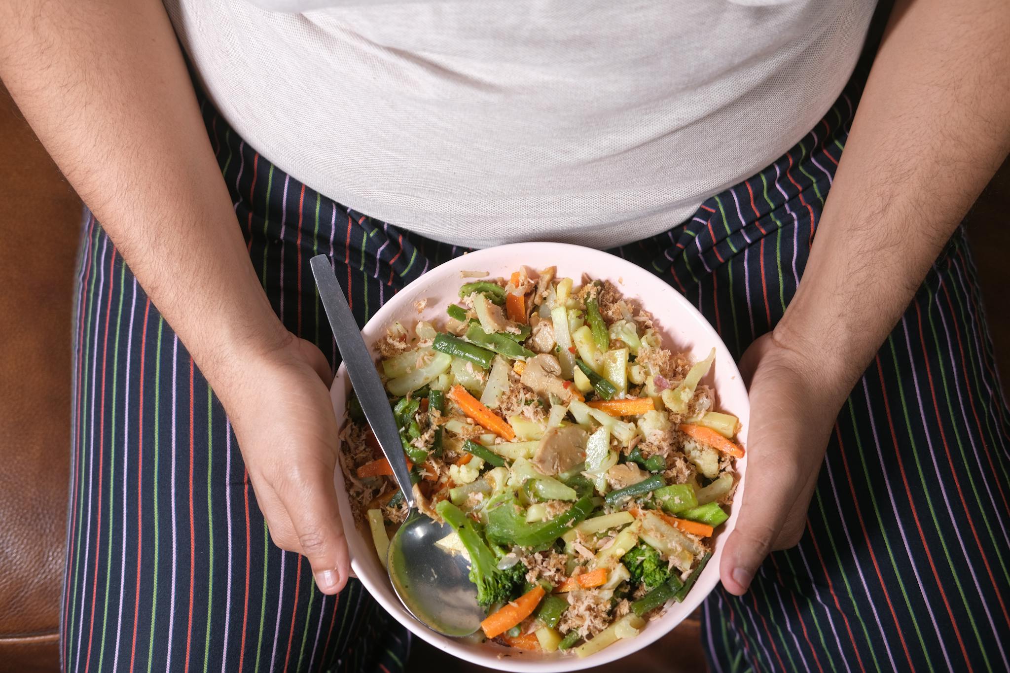 Close-up of a person holding a bowl of mixed vegetables, representing a healthy lifestyle.